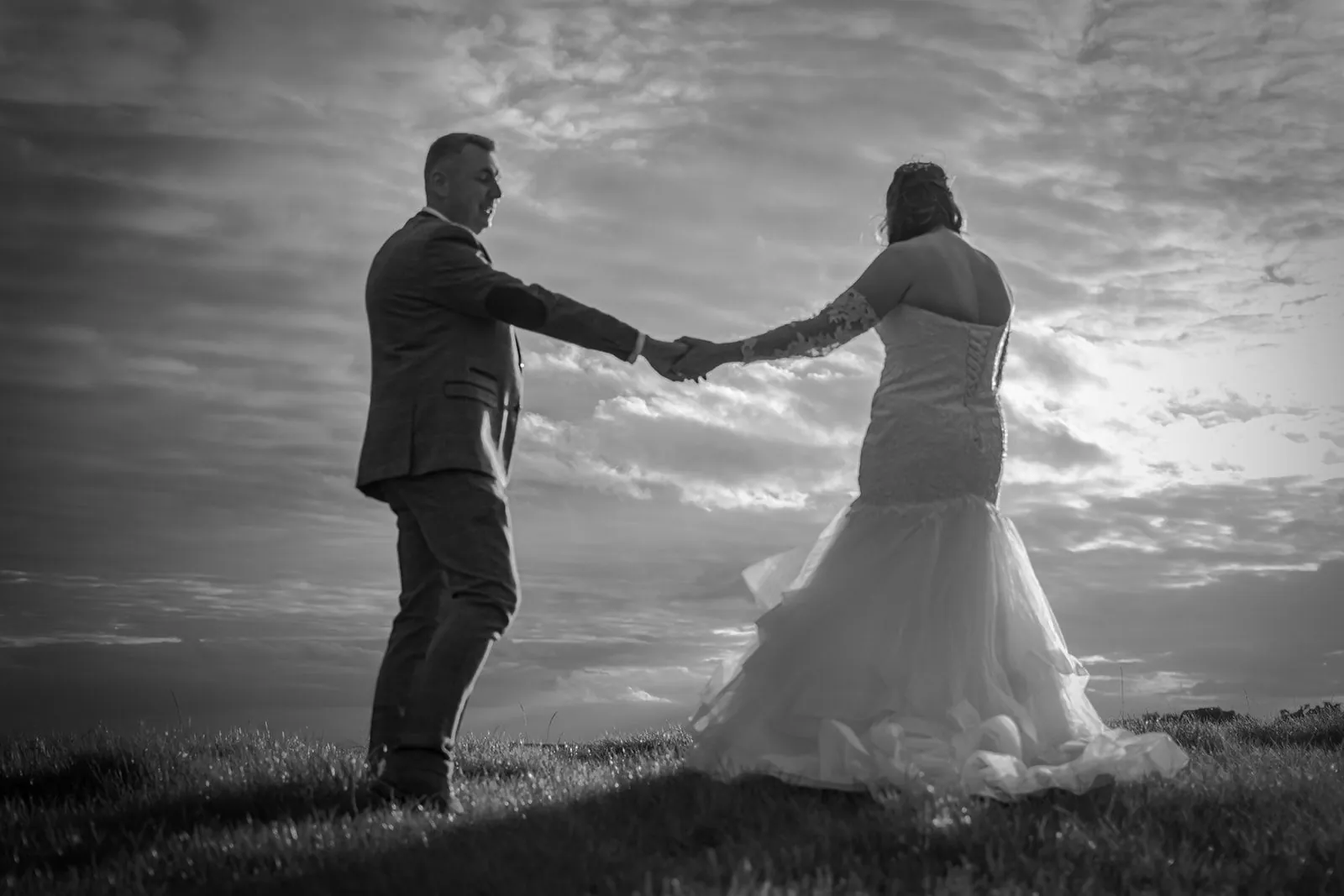 Black and white silhouette of a bride and groom holding hands on a hilltop at a Lancashire wedding