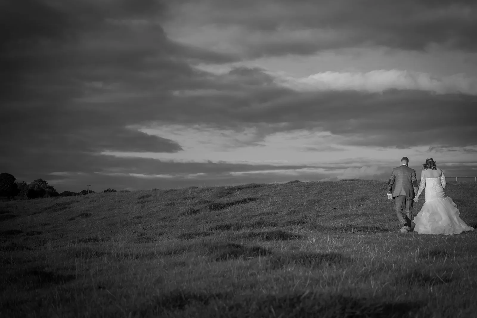 Bride and groom walking in open countryside, black and white, the kind of frame the fields around Bashall suit