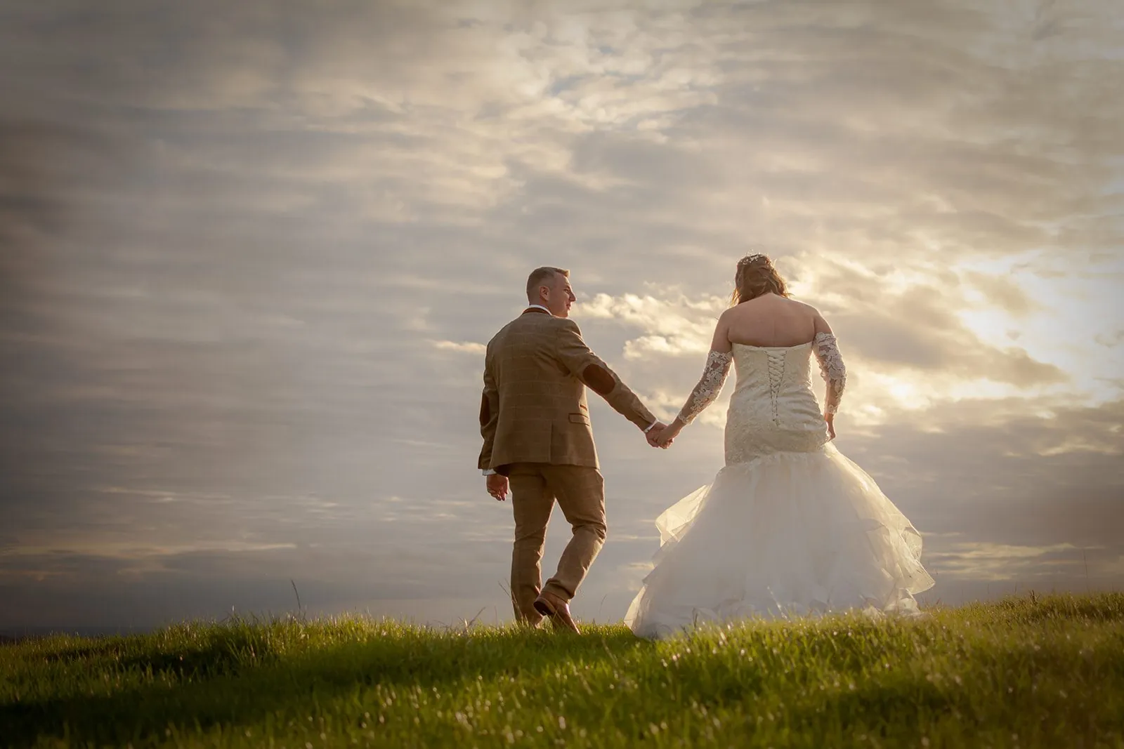 Bride and groom holding hands walking into the sunset at a Lancashire wedding