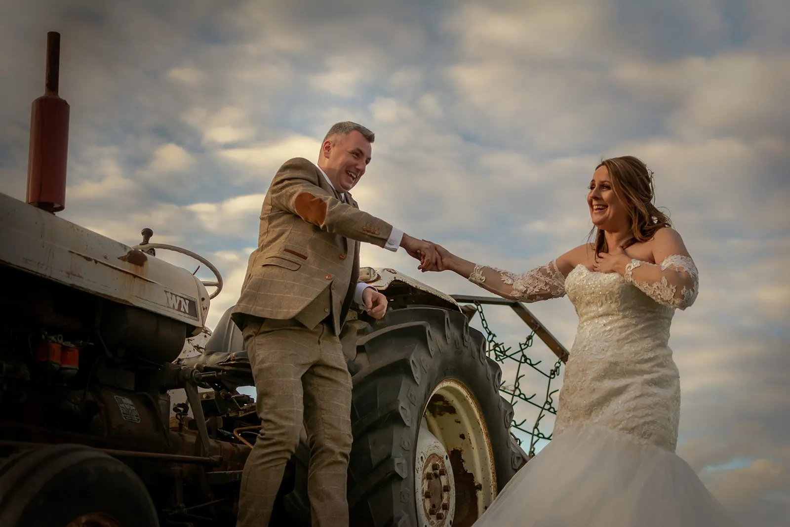 Bride and groom beside a vintage tractor at a rustic Lancashire wedding