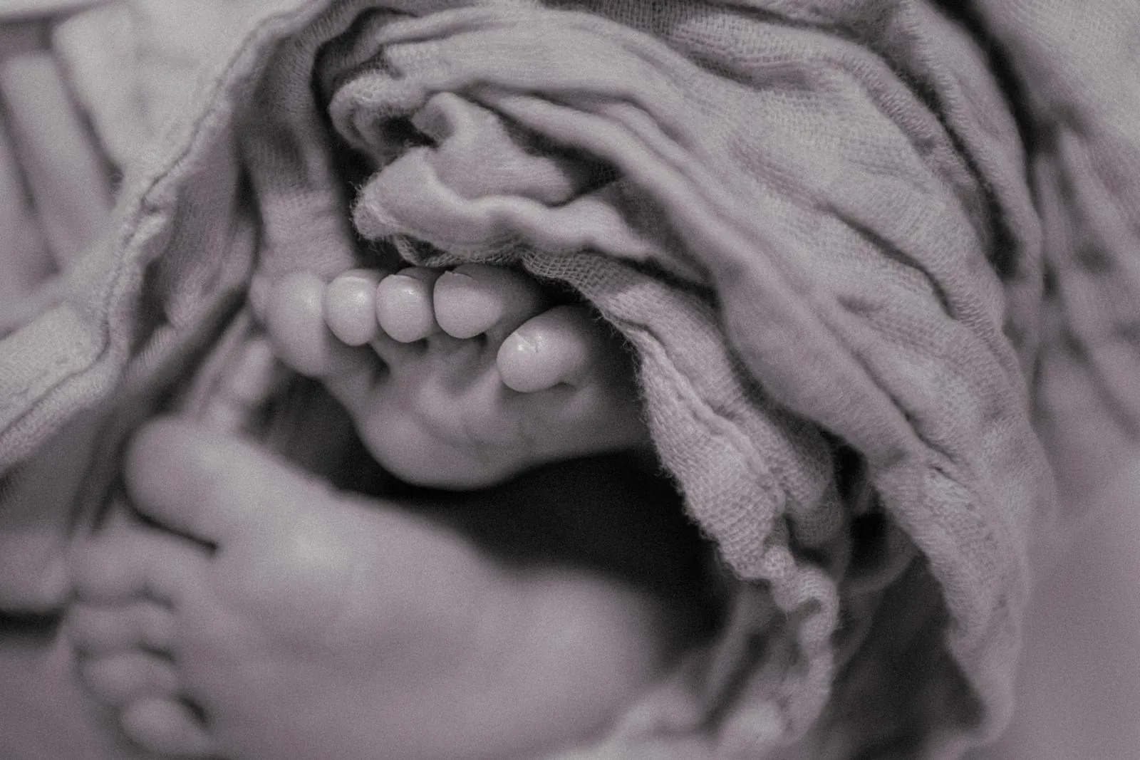Close detail of a newborn's feet in a soft wrap
